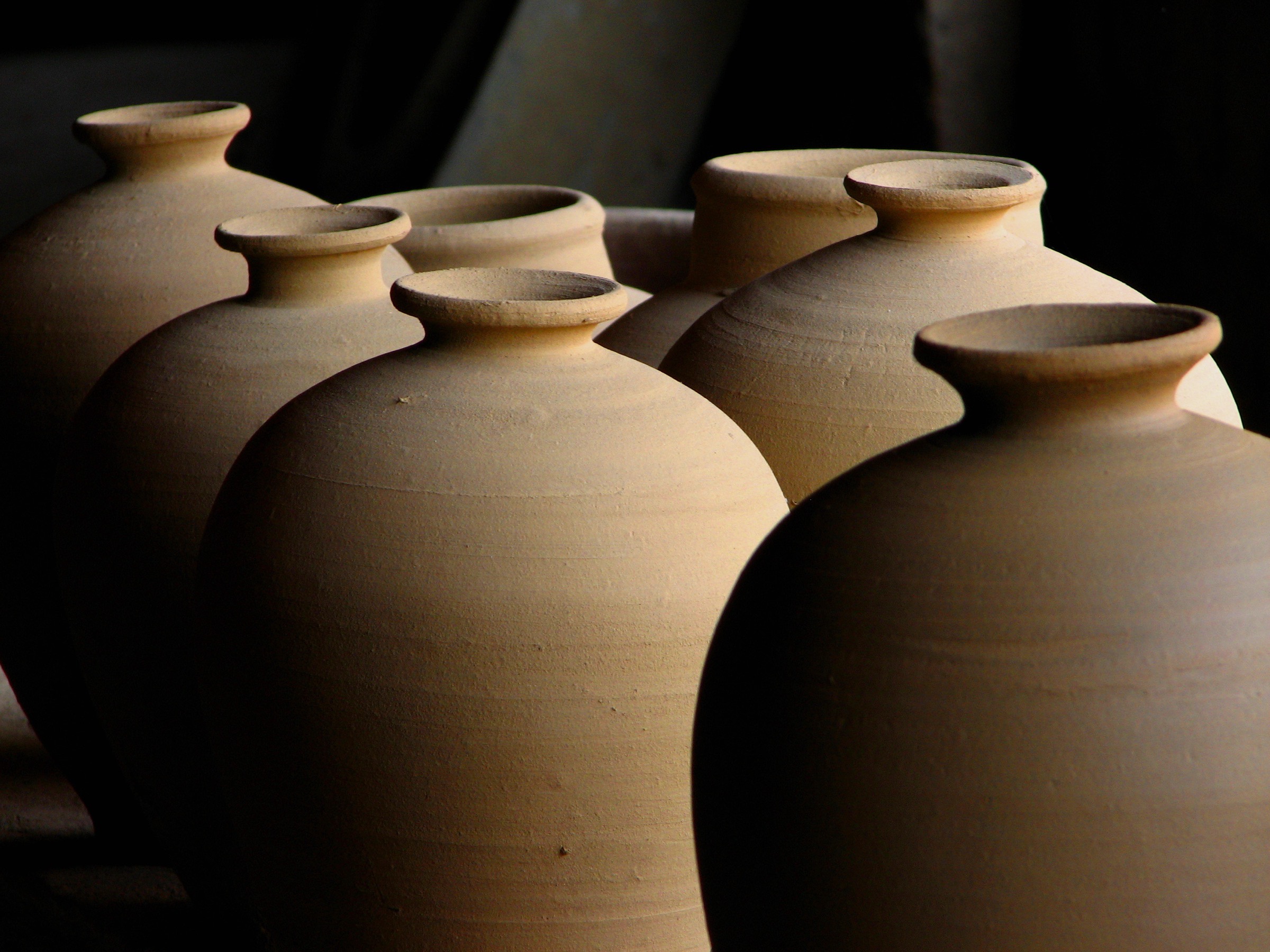 Rows of unfired clay vessels in dramatic light